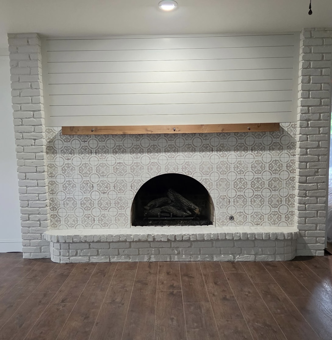 Finished fireplace with decorative tile surround, painted brick, and shiplap detail