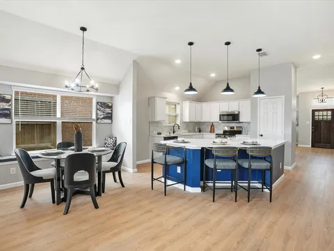 Open-plan kitchen and dining room with blue island and white cabinetry