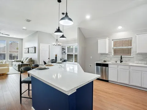 Open kitchen and living area with a blue island and pendant lighting