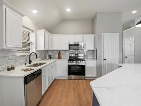 Bright white kitchen with peninsula seating and warm wood floors