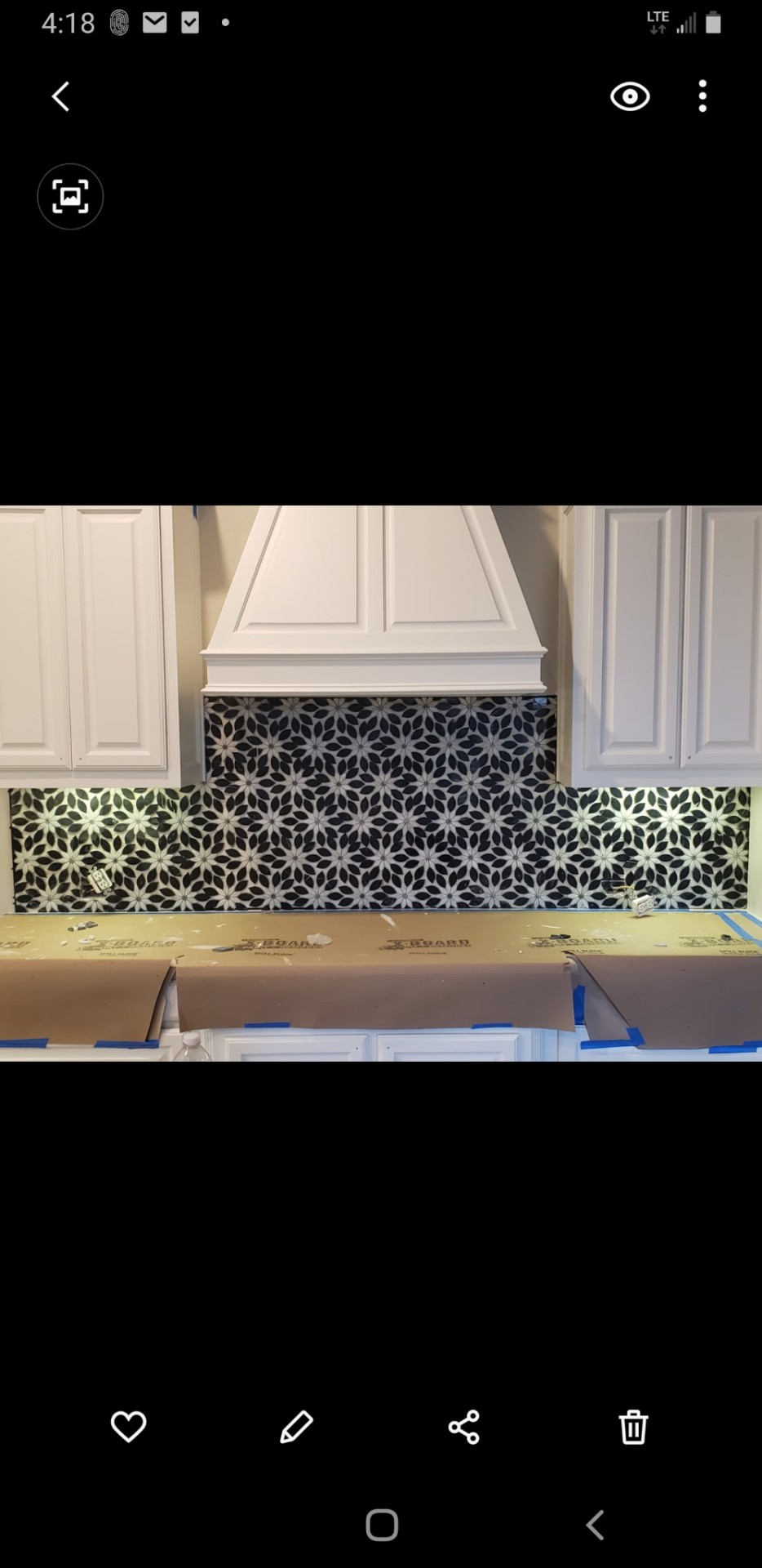 Decorative kitchen backsplash installation with patterned tile behind a range hood