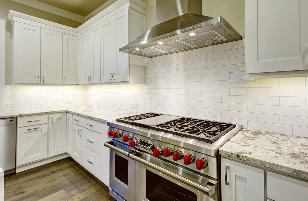 High-end kitchen range with red knobs, white cabinetry, and under-cabinet lighting