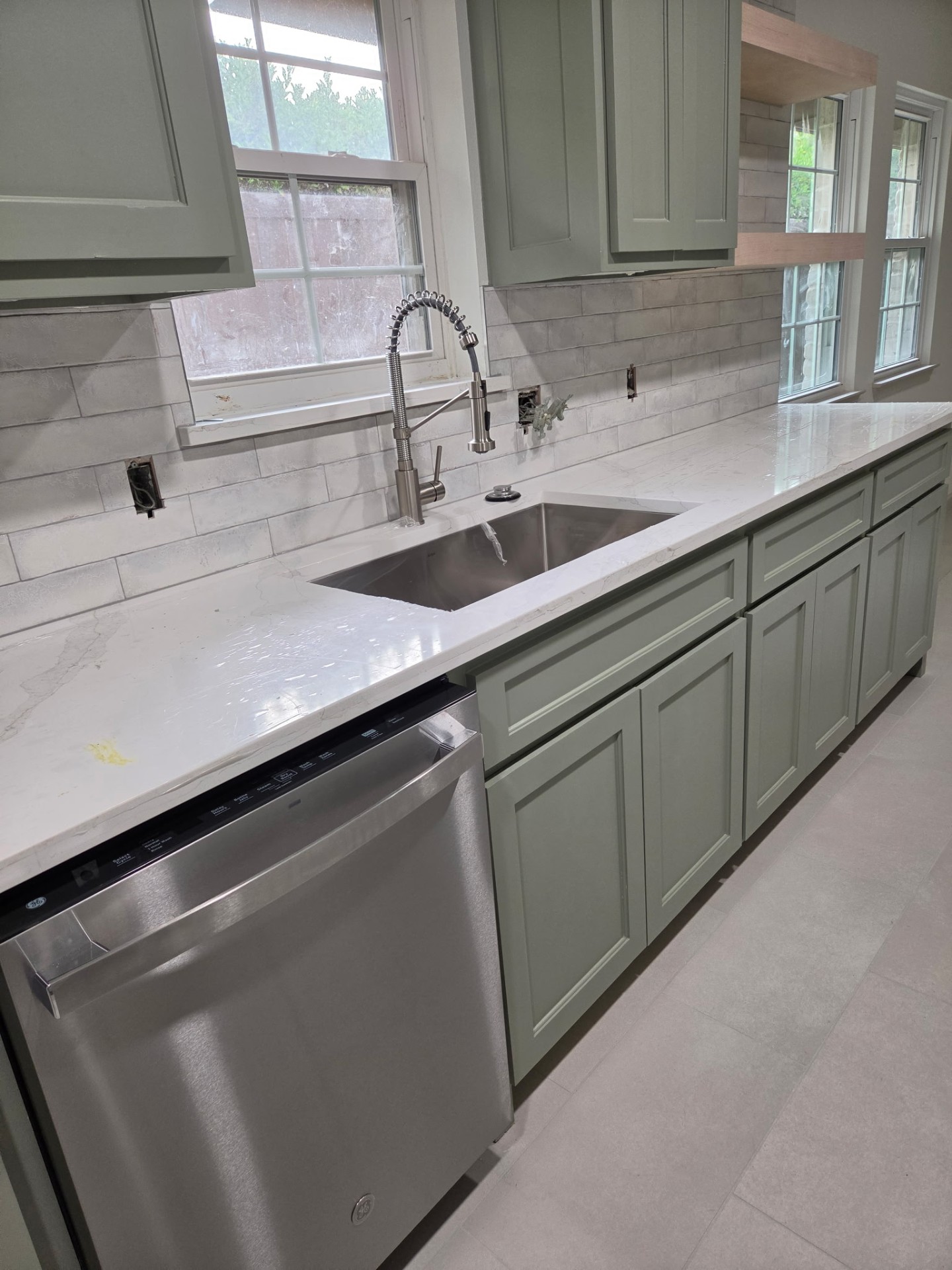 Kitchen with sage cabinetry, white countertops, and farmhouse-style faucet